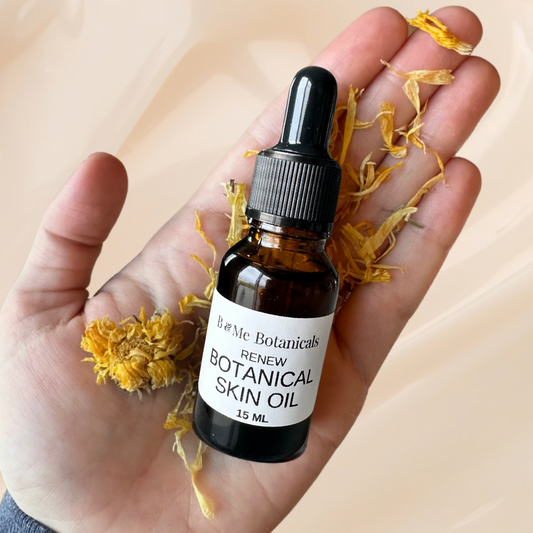A dropper bottle titled B & Me Botanicals Renew Botanical Skin Oil 15 ml in the palm of a hand with calendula petals