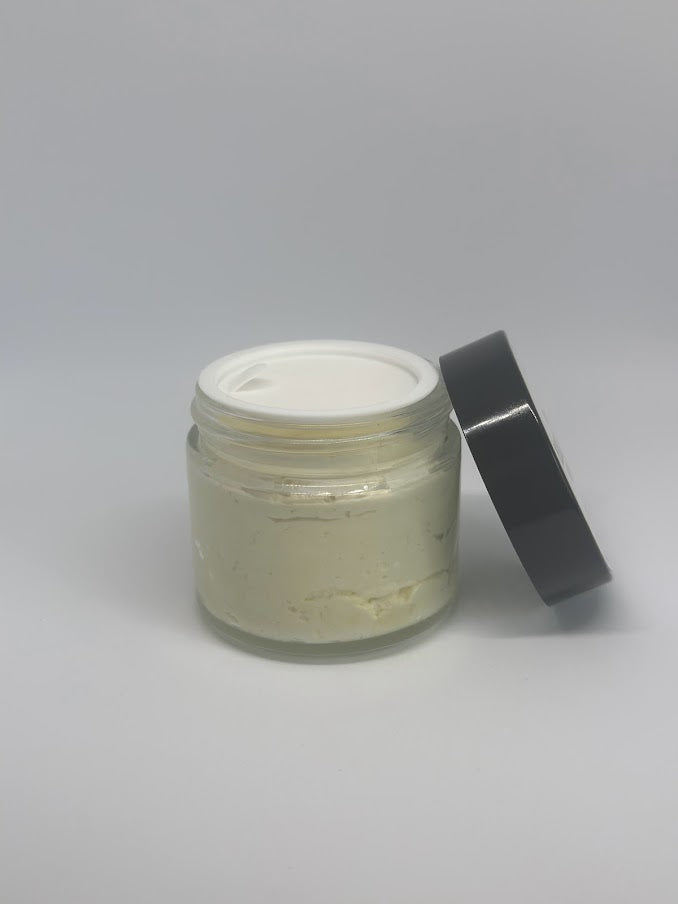 An open two-ounce glass jar of whipped lavender shea butter with a safety seal