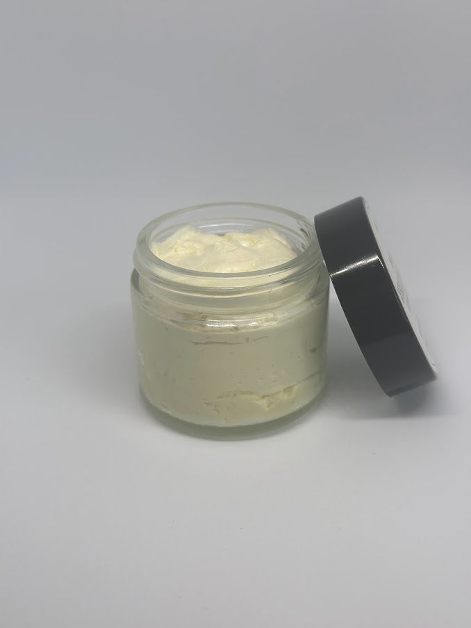 An open two-ounce glass jar of whipped shea butter